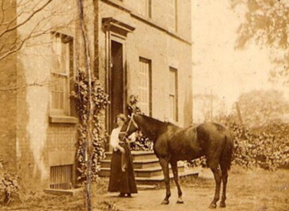 Helen Jane Matthew with a racehorse, outside a house